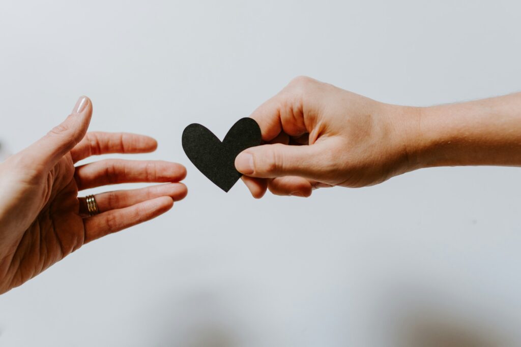 Eine Hand reicht einer anderen ein kleines Herz als Symbol für Mitgefühl und Bindungsorientierung in der NARM Traumatherapie in der Praxis Nienna von Heilpraktikerin für Psychotherapie Martina Herrmann